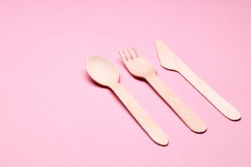 eco-friendly disposable utensills concept. bamboo or wooden cutlery over pink color background.