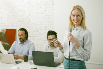 Fototapeta premium Speech of business woman at office presentation. Highlighted focus on the microphone in the hand of a business woman.