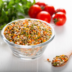 Colorful various beans or lentils and whole grains seeds or cereal in bowl with fresh vegetables on wooden background.