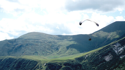 Obraz premium Paraglider flying over mountains during summer day - Georgia, kazbegi