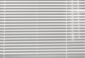 Window shutters. Closeup white color blind with white ladder tape curtains. Window with open modern horizontal blinds indoors