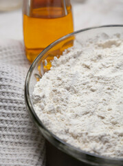 Plate with flour on the background of a bottle of oil. Macro