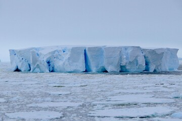 Large blue iceberg at edge of pack ice in antarctic ocean, Antarctica