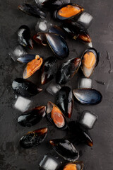 Fresh mussels with ice, seafood. Shellfish on a stone dark table, top view, macro