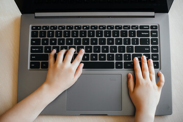 Hands of a child close-up on the laptop keyboard. Distance learning. Stay at home