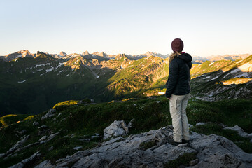 Obraz premium Young woman is looking at Allgäu Mountains near Oberstdorf in the german Alps during sunrise on a clear refreshing morning