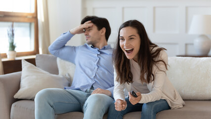 Bored boyfriend feel annoyed dissatisfied for girlfriend cheering watching football game match on...