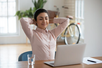 Peaceful young indian businesswoman relaxing with closed eyes at workplace. Calm millennial female...