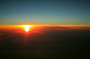 bright red sun in a high sky view from the plane window