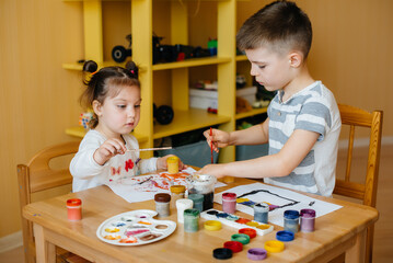 A boy and a girl play together and paint. Recreation and entertainment. Stay at home