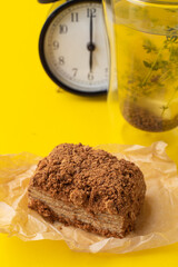 Minimalist stylish food photoshoot in a studio: healthy honey cake with a glass of herbal tea on yellow background
