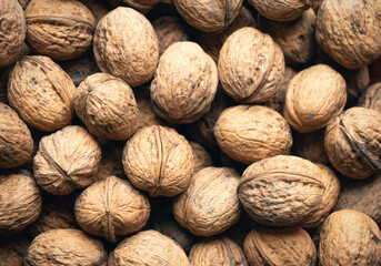 Heap of whole walnuts - full frame natural pattern background detail. Close up of a brown surface texture of walnut shells. Healthy organic food, BIO viands, back to nature concept. Copy space