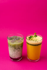 Two glasses of sweet matcha beverages, top view on bright magenta background
