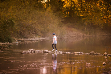 Fototapeta na wymiar Little blonde girl on the riverside. Autumn in the yellow forest