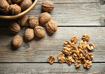 Fresh walnut kernels and whole walnuts in a bowl on rustic old wooden table. Healthy organic food, BIO viands, natural background. Copy space for your advertising text message