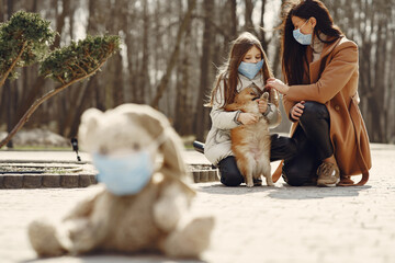 Family walks outside. Coronavirus theme. Mother with daughter walking the dog. Toy in a mask.