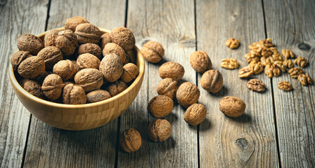 Fresh walnut kernels and whole walnuts in a bowl on rustic old wooden table. Healthy organic food, BIO viands, natural background. Copy space for your advertising text message