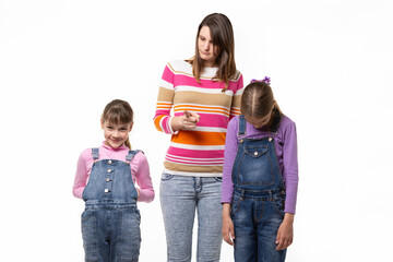 Mom scolds children, one girl smiles another stands wilted