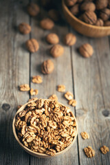 Fresh walnut kernels and whole walnuts in a bowl on rustic old wooden table. Healthy organic food, BIO viands, natural background. Copy space for your advertising text message