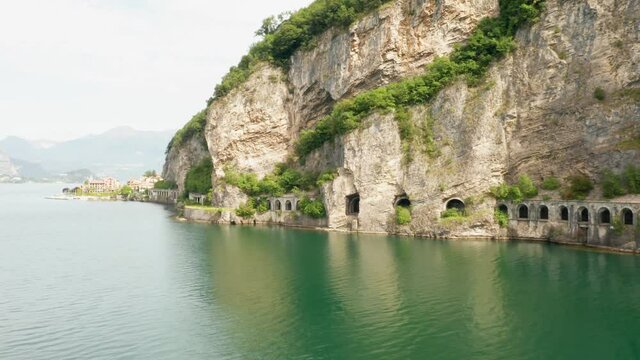 Aerial shooting along Grumo tunnel in granite mountain with green trees next to Como Lake, Lecco, Italy 