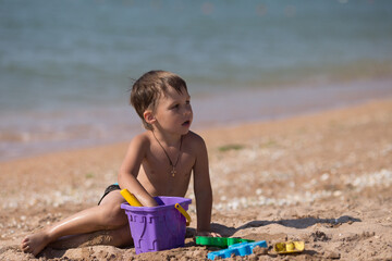 little boy playing on the beach with sand