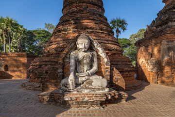Fototapeta na wymiar Ancient Buddha statue among the ruins of Yadana Hsemee pagoda in the royal city of Ava, Inwa, Myanmar