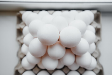 A tray of white fresh eggs in close-up laid out by a pyramid on a cardboard package. Agricultural industry