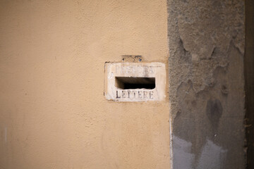 Antique plastered wall with a hole for mail letters. pretura lettere, inscription near the hole.