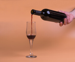 a bottle of red wine and a glass on a beige background