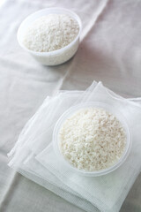 raw white rice in bowl, on white cloth background