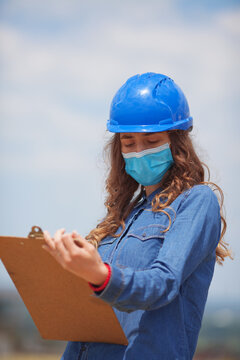 Young Woman Engineer Wearing Face Mask And Holding Clipboard With Documents