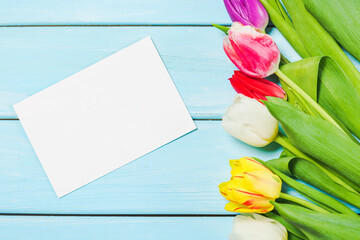 Colorful spring tulip flowers with blank photo on light blue wooden background as greeting card. Mothersday or spring concept.