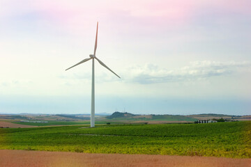 Modern windmills for power supply are installed in an open space in a field.