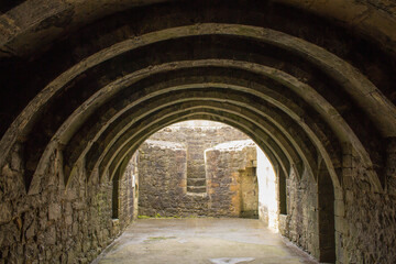 Fototapeta na wymiar Barrel-Vaulted Basement of Crookston Castle in the Pollock Area in Glasgow, Scotland. Photo Showing Cellar Style Arch Ceiling and Stone Walls. Free Entry to the Publick