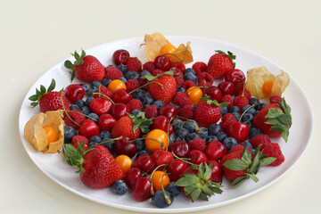 Plate with different berries - strawberries, raspberries, blueberries 