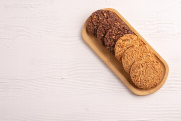 Stack of tasty chocolate cookies on white wooden table.