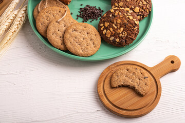 Stack of tasty chocolate cookies on white wooden table.