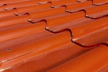 Bright red roof tiles background. Metal roofing. Construction materials, architecture, roof cover.