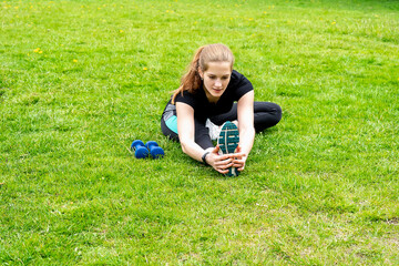 Girl workout before jogging in the park. On the ground nearby are dumbbells.