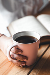 Woman in a white t-shirt holds morning coffee in a pink ceramic cup. Manicure. Front view