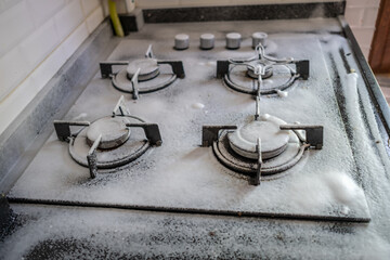 Cleaning a gas stove on a sunny day. Kitchen cleaning