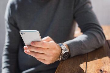 joven utilizando su celular con su mano izquierda para enviar un mensaje