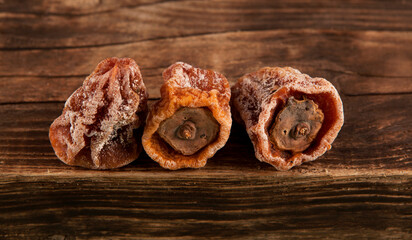 Dried Persimmon (Hoshigaki). Textured wrinkled fruits on a wooden background. Useful sweets