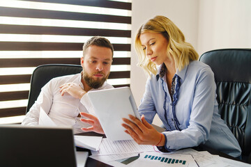 Young caucasian adult man and woman at office looking digital tablet