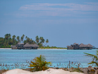 Tourist bungalows near a exotic island are surrounded by the turquoise ocean.