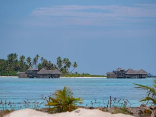 Foto op Canvas Tourist bungalows near a exotic island are surrounded by the turquoise ocean. © helivideo