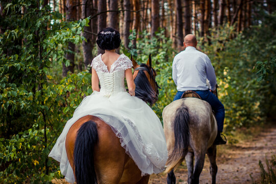 bride and groom riding horses in the forest