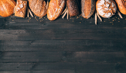 Bread border on black wood background with copy space. Composition of black, brown and white whole...