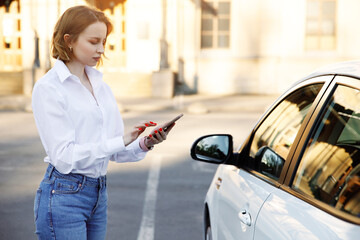 Woman using mobile phone, communication or online application, standing near car on city street or...
