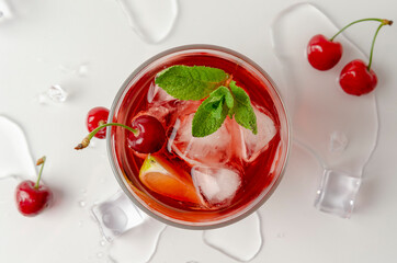 refreshing red cocktail with sparkling water and ice garnished with a lime and cherry